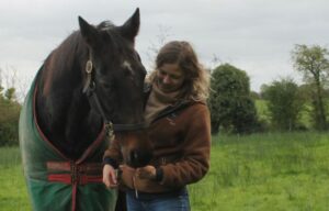 Owner of IF Equine Therapies and horse standing in a field