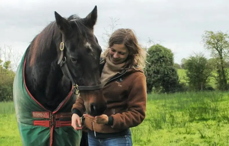 Owner of IF Equine Therapies and horse standing in a field